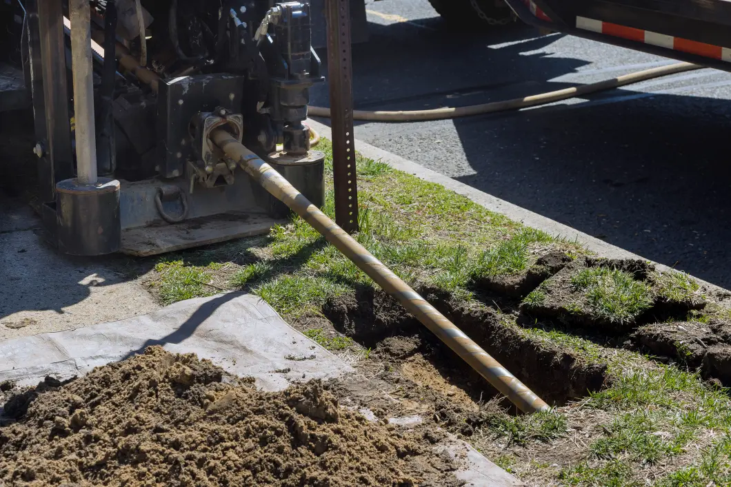 Patriot Trenchless Plumbing horizontal boring rig running a new pipe beside a driveway and lawn in Illinois without tearing up the surface.