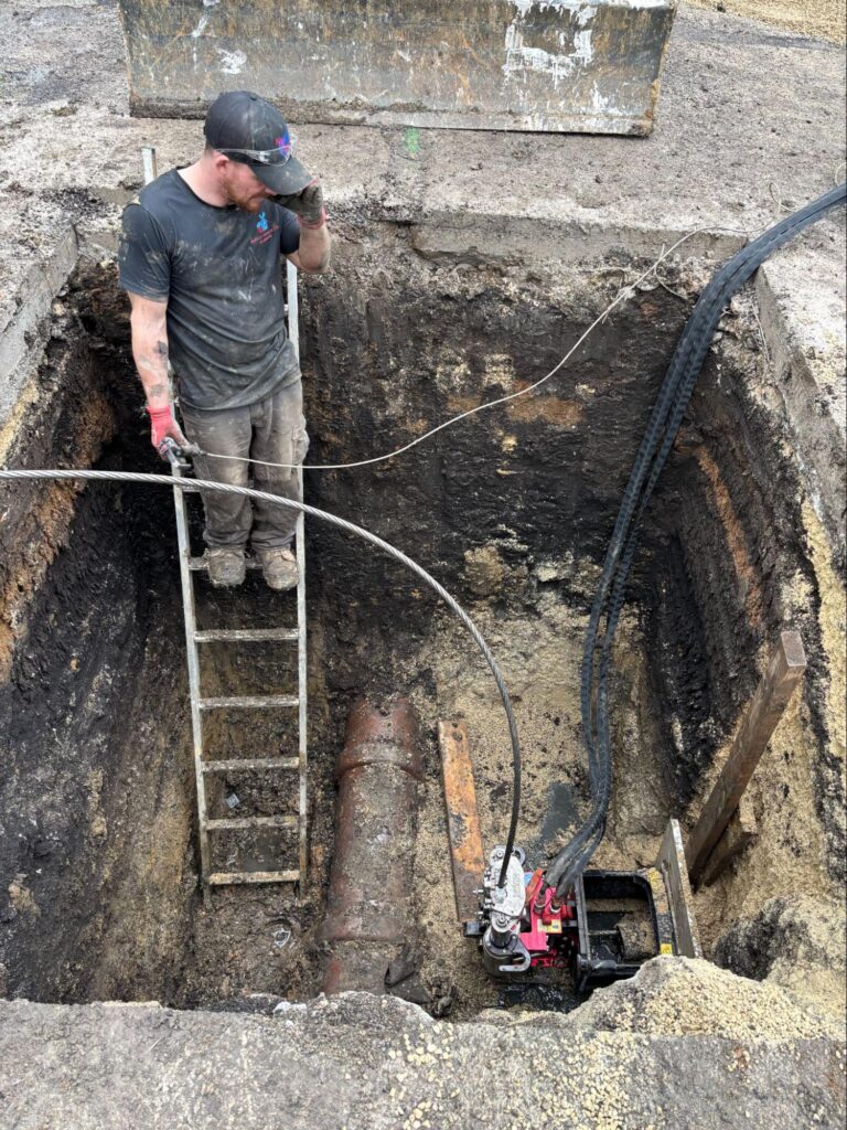 Patriot Trenchless plumber entering an access pit during a Fox Valley pipe bursting job.