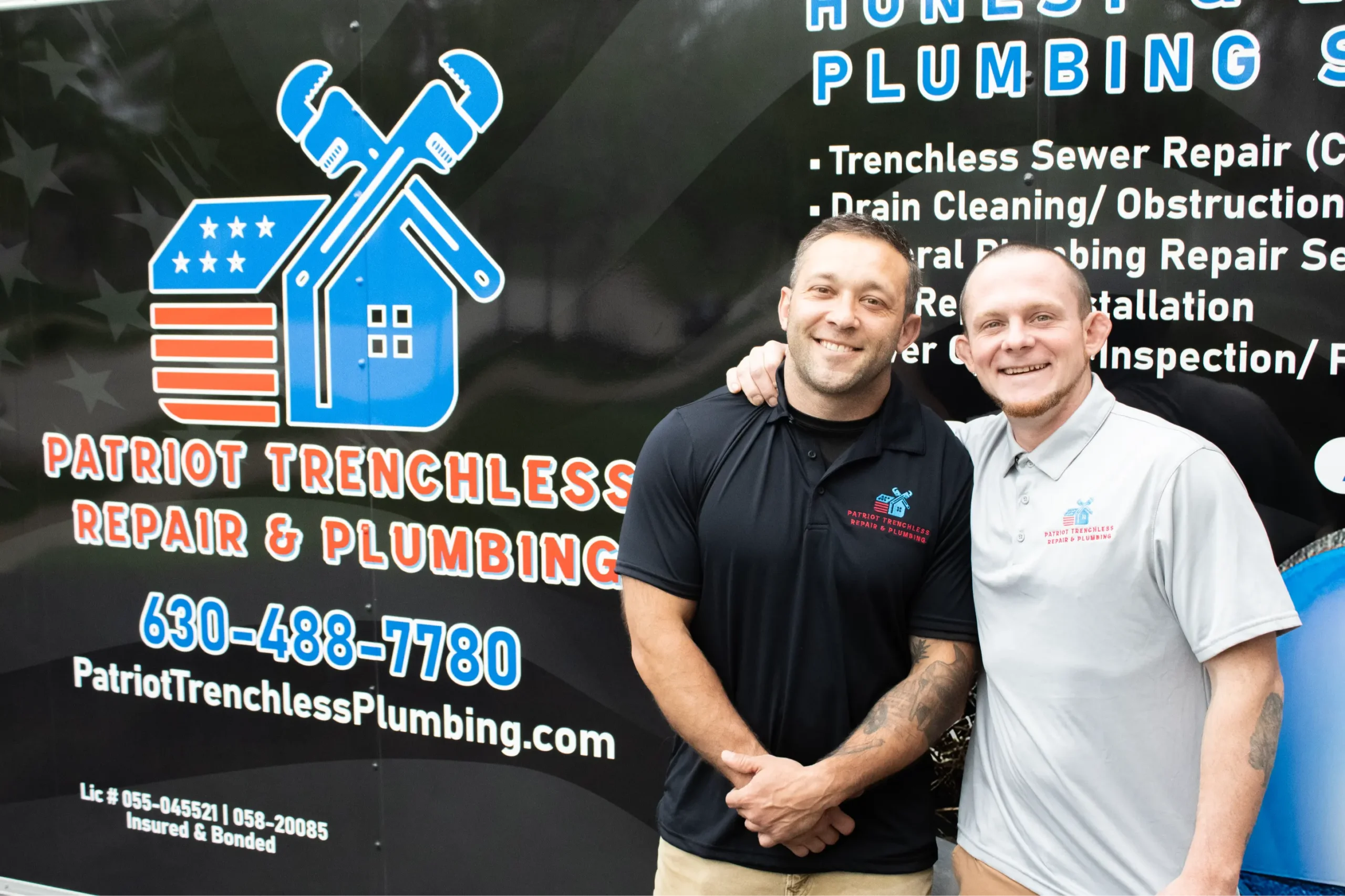The veteran owners of Patriot Trenchless Plumbing standing in front of their branded service truck