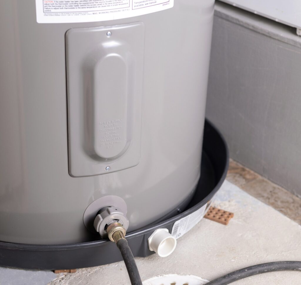Old electric water heater drained through a hose before a new water heater installation.